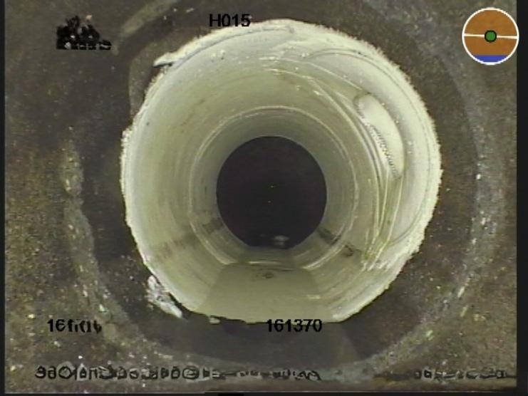 Blick in ein Rohr mit glatten Wänden und dunklem Innenbereich, kleine Ablagerungen an den Rändern sichtbar.