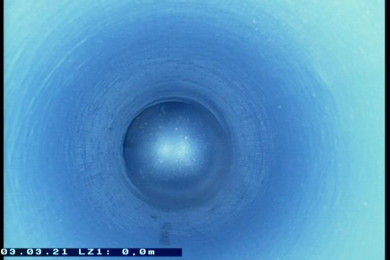 Blick in einen blauen, zylindrischen Rohrinneren mit glatter Wand und einem hellen Punkt in der Mitte.