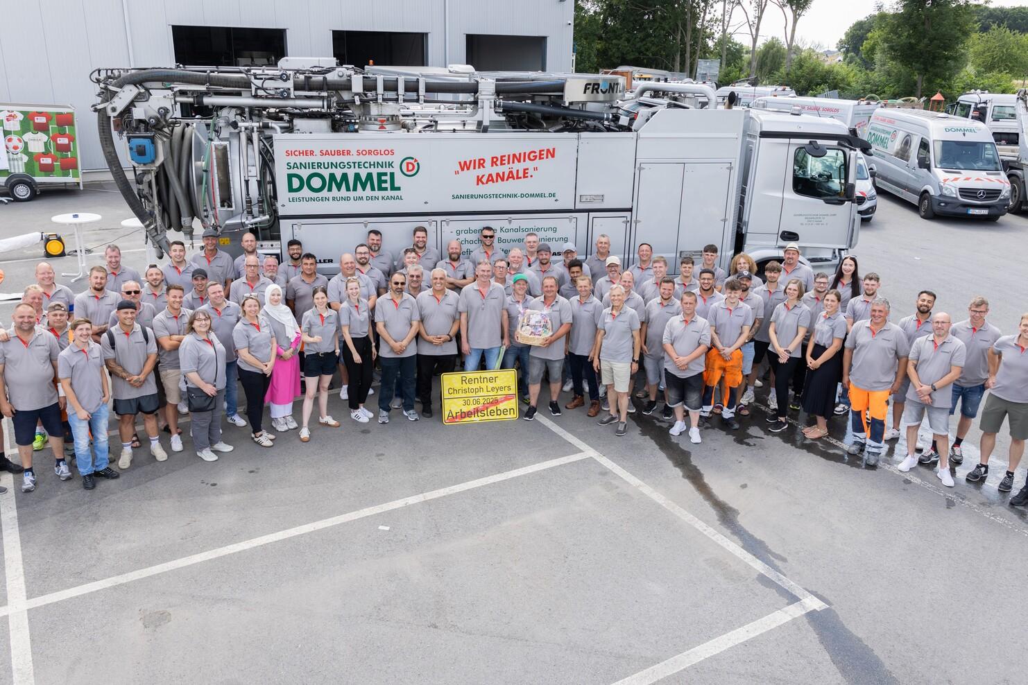 Gruppenfoto von Mitarbeitern der Firma Dommel vor einem Fahrzeug mit dem Schriftzug „Wir reinigen Kanäle“.