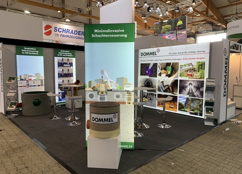 Messestand mit Werbung für grabenlose Rohrsanierung, inklusive Modellen und Informationen zu Dienstleistungen.