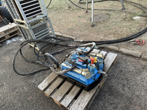 Blaue Maschinenkomponente mit Schläuchen auf einer Holzpalette, im Hintergrund sind weitere Geräte sichtbar.