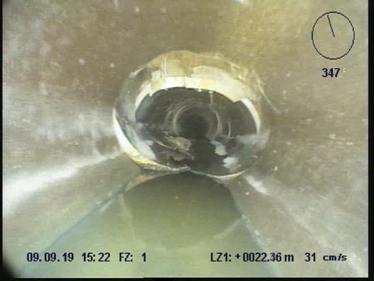 Kamerablick in ein Rohr mit Wasser und schmutzigem Innenbereich, vom Rohrende betrachtet.