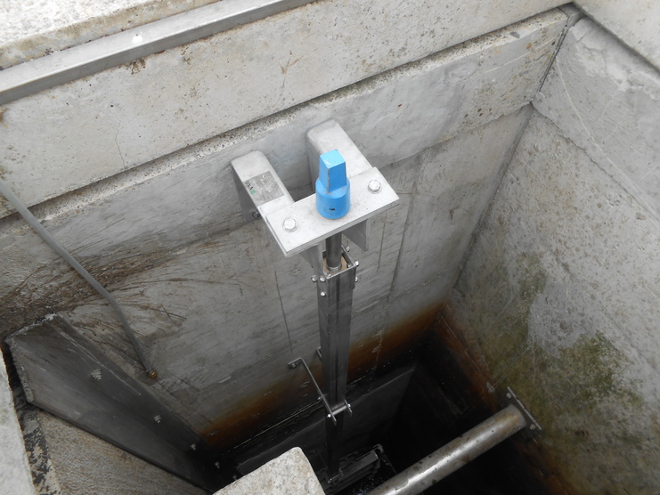 Blick auf einen vertikalen Schacht mit einem Metallgestell und einer blauen Steuerungseinheit in der oberen Ecke.