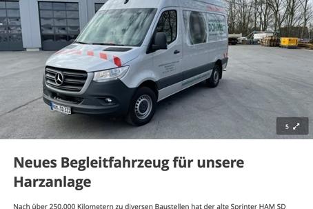 Weißer Mercedes Sprinter mit rot-weißer Signalmarkierung vor einer Lagerhalle, bereit für den Einsatz als Begleitfahrzeug.