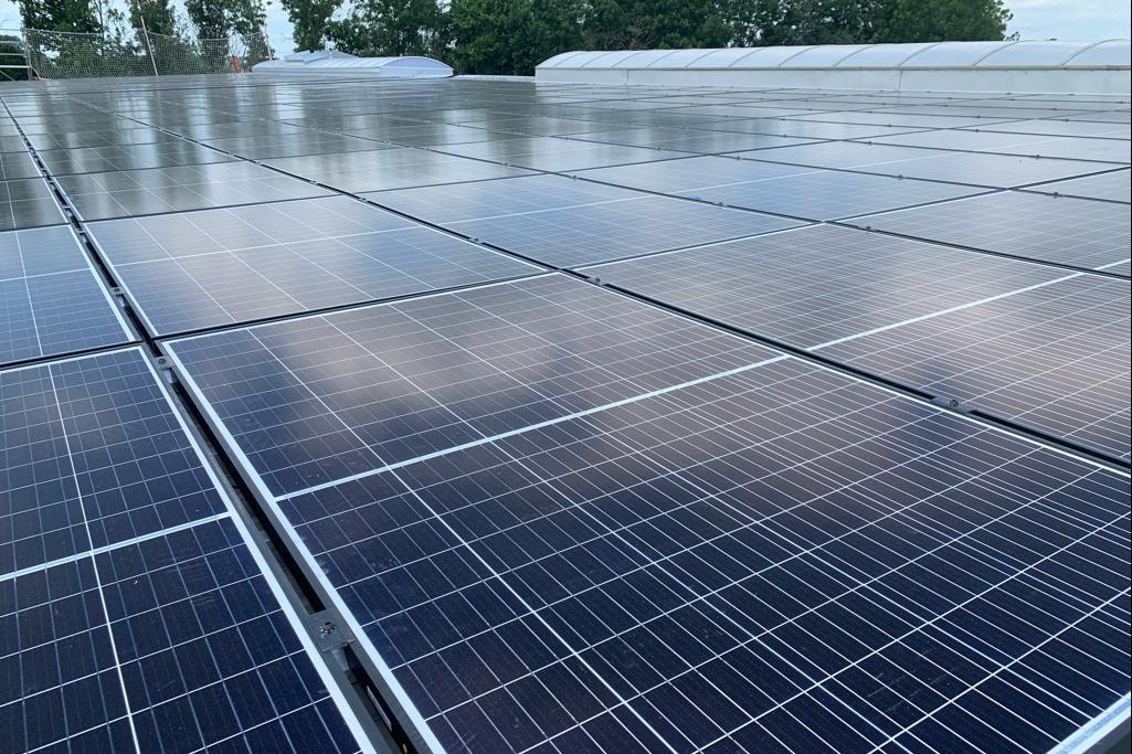 Nahaufnahme eines Dachs mit Photovoltaik-Modulen unter einem bewölkten Himmel.