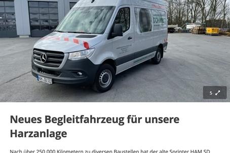 Weißer Mercedes Sprinter mit rot-weißer Signalmarkierung vor einer Lagerhalle, bereit für den Einsatz als Begleitfahrzeug.