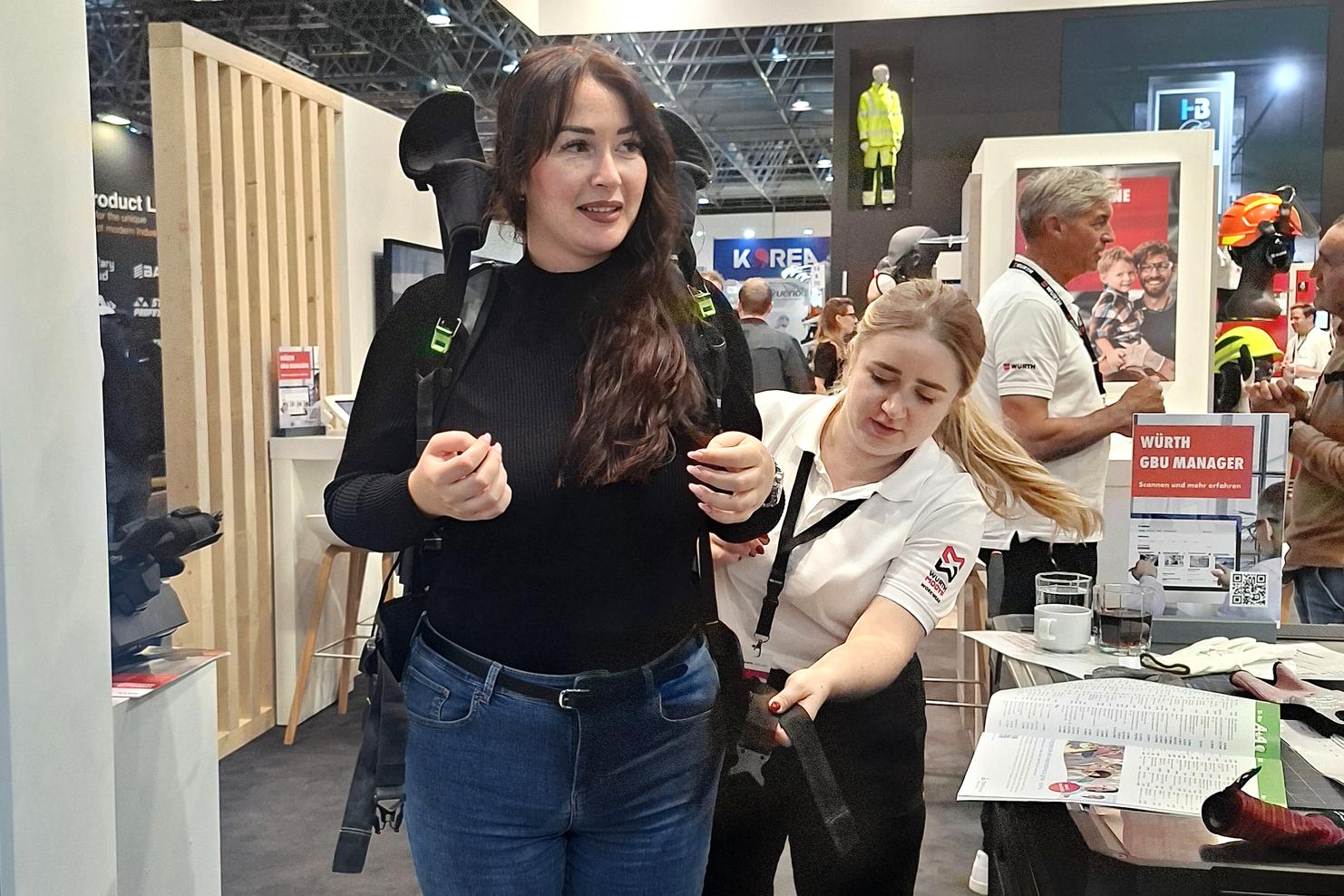 Frau mit Rucksack und anpassendem Gurt während einer Demonstration an einem Messestand.
