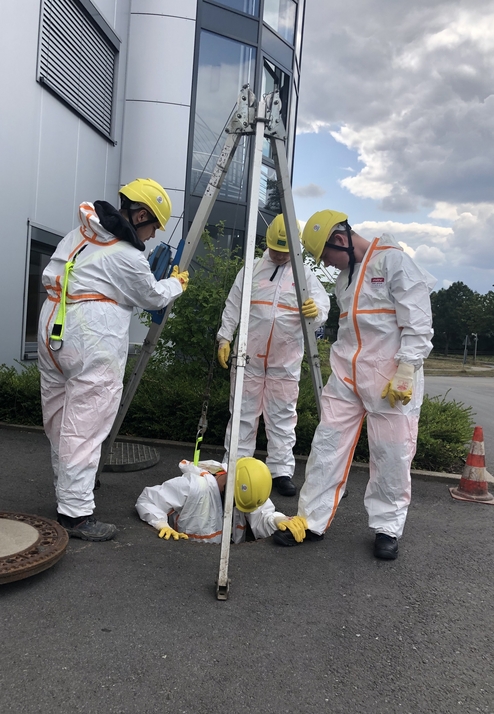Vier Personen in Schutzanz&uuml;gen und Helmen arbeiten an einem Schacht, eine Person ist teilweise darin.