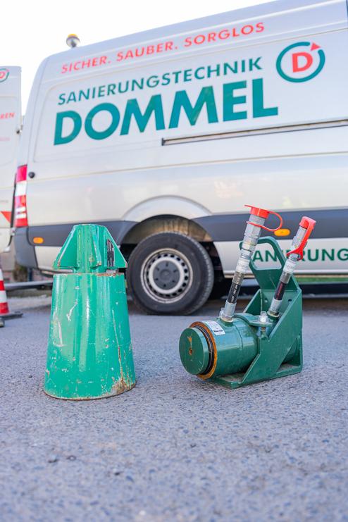 Grüne Materialien für Sanierungstechnik: ein konischer Kegel und eine Pumpe stehen auf asphaltierter Oberfläche.