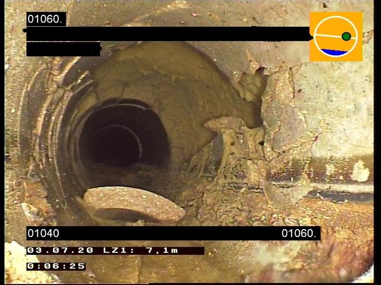 Blick in ein Rohr mit Ablagerungen und einer offenen Stelle, die die Innenstruktur sichtbar macht.