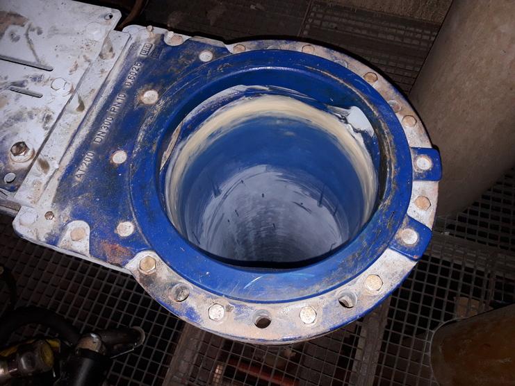 Blick in ein blaues Rohr mit schmutziger Innenfläche, umgeben von einer metallenen Flanschkonstruktion.