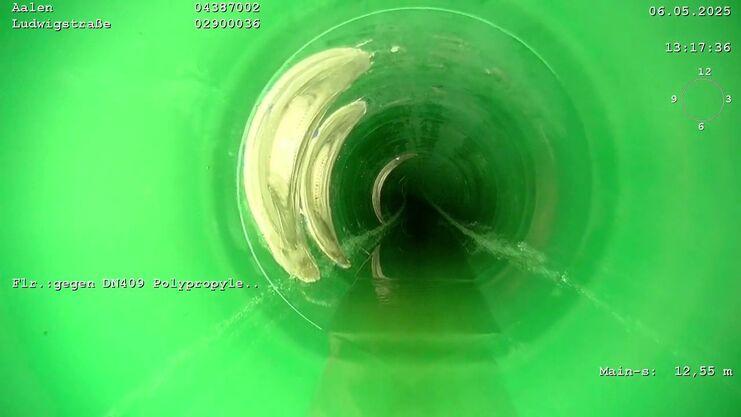 Blick in ein grünes Rohr mit Wasserfluss und reflektierenden Wänden, aufgenommen in Aalen, Ludwigstraße.