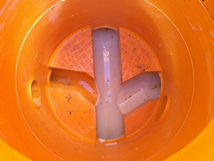 Innenansicht eines orangen Behälters mit mehreren Rohren und einem gestanzten Boden. Leichte Ablagerungen sichtbar.