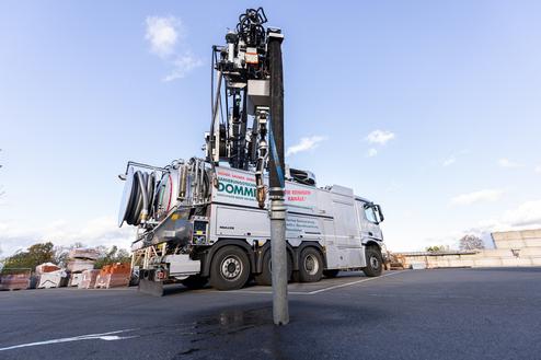 Lkw mit Sanierungstechnik steht auf einem Parkplatz, in der Nähe einer Betonwand und Baustellenmaterialien.