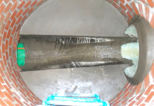 Blick ins Innere eines Ziegelkanals, Wasser strömt durch ein Rohr mit grünem Markierung.