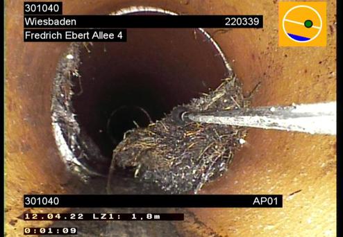 Kameraansicht in einem Abflussrohr mit verstopfendem Material und einer Reinigungsstange, Tiefenanzeige 1,8 m.