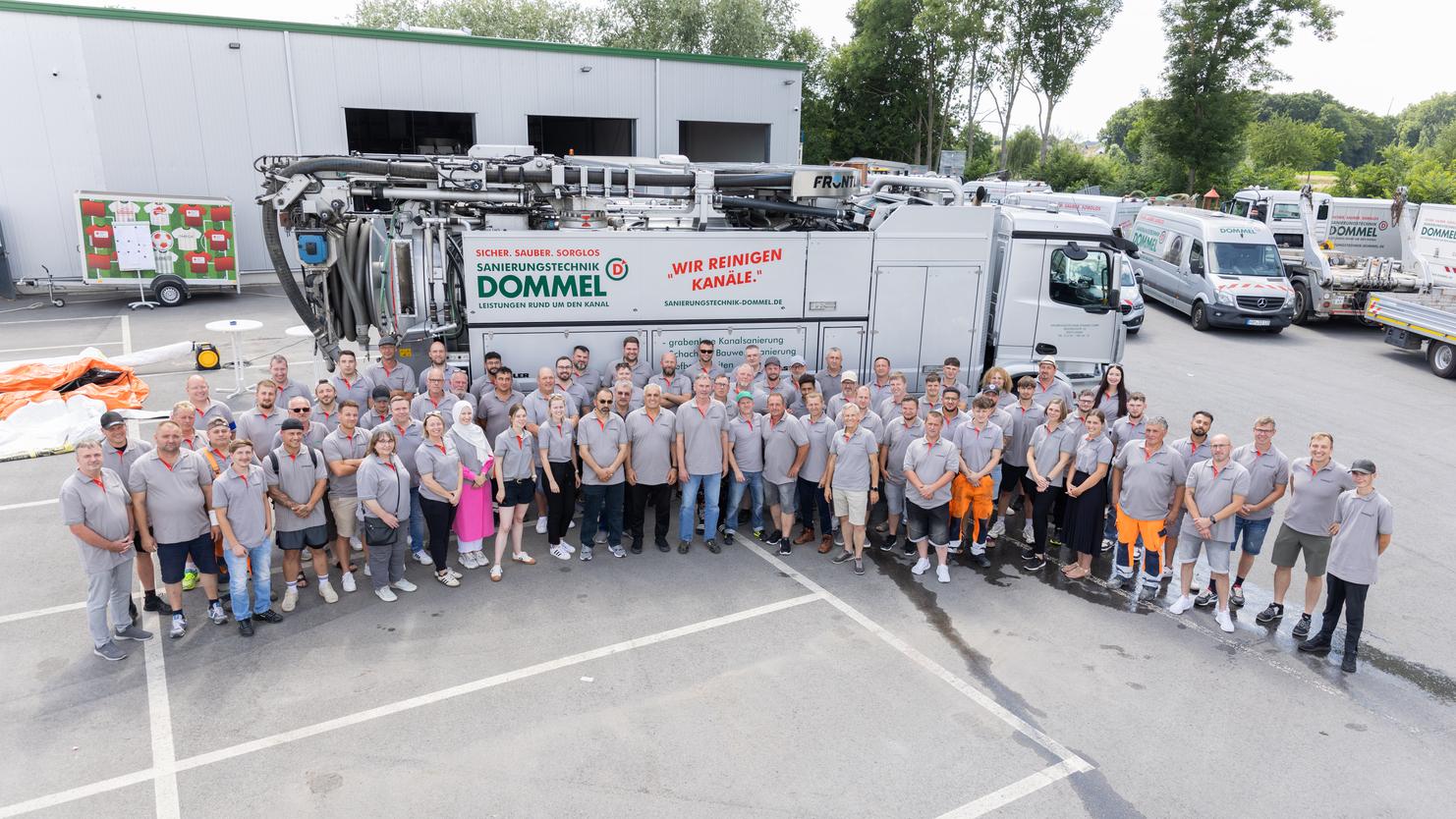 Gruppenfoto des Teams von Donmel vor einem Fahrzeug zur Kanalreinigung, umgeben von weiteren Transportern.
